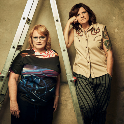 The Indigo Girls (Amy Ray and Emily Saliers) stand beside a ladder